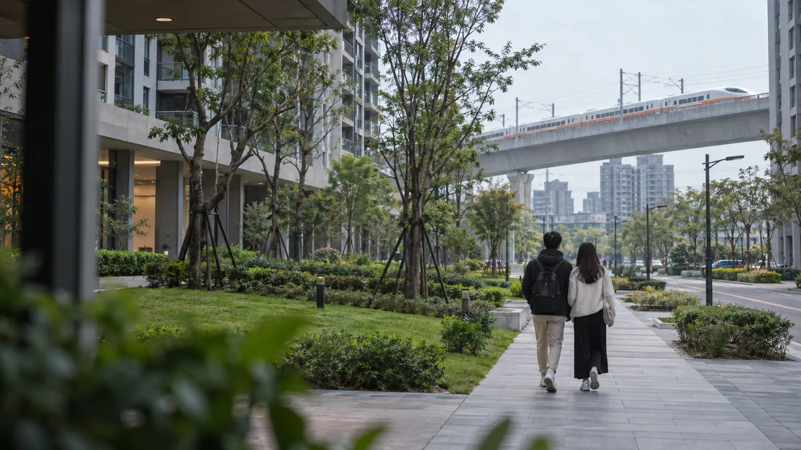 高鐵列車行經社區旁,年輕夫妻在寬敞綠意步道悠閒漫步。